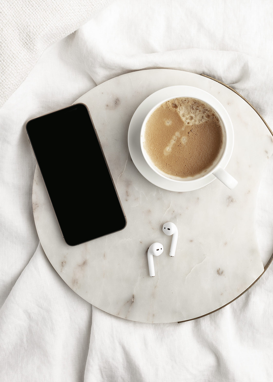 Smartphone für Apps für mehr Produktivität liegt auf einem Tablett mit Kopfhörern und einer Tasse Kaffe.